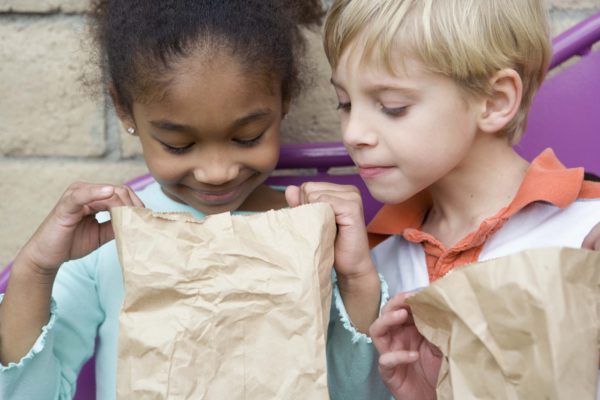 Boy looking in friends lunch bag at recess
